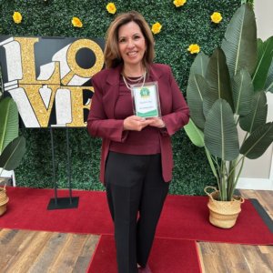 Owner lisa ciao of Maid For You posing with her award for best cleaning service in front of a LOVE sign and green background on red carpet at the bucks county parent love awards